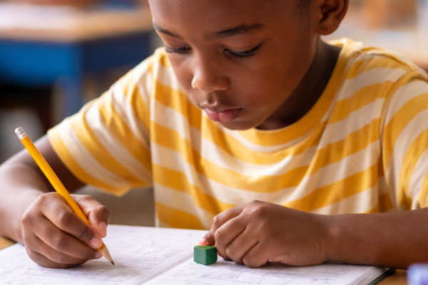 A child with ADHD concentrating on solving math problems in a classroom setting with supportive learning materials.